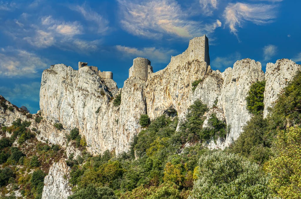 Explore the medieval Peyrepertuse Castle perched on limestone cliffs in a stunning French landscape.